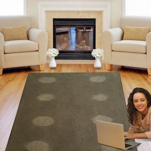 May include: A dark gray area rug with light gray circular patterns. A laptop computer and a woman are on the rug. The rug is in a living room with a fireplace and two armchairs.