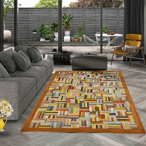 May include: A colorful, multi-colored, rectangular rug with a geometric pattern. The rug has a brown border and is made of woven fabric.