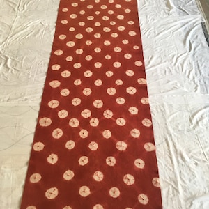 May include: A long, rectangular rug with a rust-colored background and a pattern of white circles.