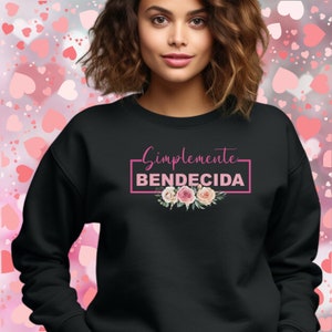 May include: Black sweatshirt with the text "Simplemente BENDECIDA" in pink lettering with a floral design below the text.