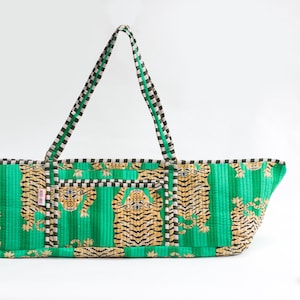Puede incluir: Un bolso tote verde con estampado de tigre. La bolsa presenta un dise&ntilde;o acolchado con rayas verticales y un patr&oacute;n repetido de tigres en tonos marrones y negros. Las asas son a rayas en negro, blanco y verde.
