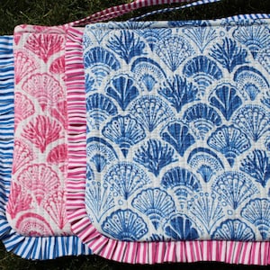 Könnte beinhalten: Zwei gequiltete Stoff-Platzsets mit einem blauen und weißen Muschelmuster und einem rosa und weißen Muschelmuster. Beide Platzsets haben einen weißen und rosa gestreiften Rand.