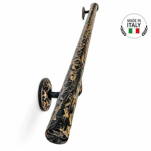 May include: A wall-mounted handrail featuring a textured, cylindrical bar with a black and gold finish. The handrail is supported by two circular mounting brackets with matching black and gold detailing. A circular logo reads MADE IN ITALY.