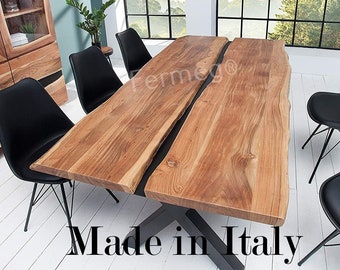May include: A rectangular dining table featuring two thick, natural live-edge wood slabs with a visible grain pattern, separated by a central gap, supported by a black metal X-shaped base, accompanied by four black chairs with thin metal legs.