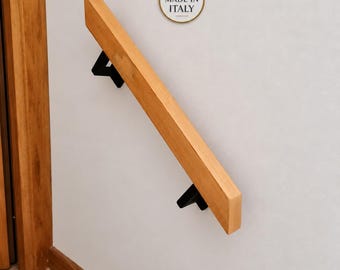 May include: A light brown wooden handrail mounted diagonally on a wall with two black metal brackets. Above the handrail is a circular white badge with the Italian flag colors and the text MADE IN ITALY printed in black capital letters.