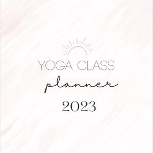 May include: A white background with a subtle pink watercolor design. The text "YOGA CLASS planner 2023" is centered on the page. A stylized sun graphic is above the text.