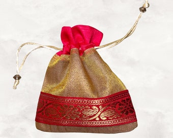 May include: A small, gold and red drawstring bag with a decorative border. The bag is made of a sheer fabric and has a pink lining.