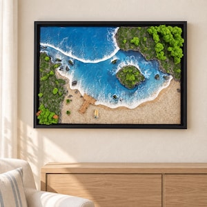 May include: A rectangular wall art piece featuring a 3D coastal landscape with blue resin water, white foam waves, a sandy beach, green mossy vegetation, a small wooden pier, and a tiny boat, all enclosed within a black frame.