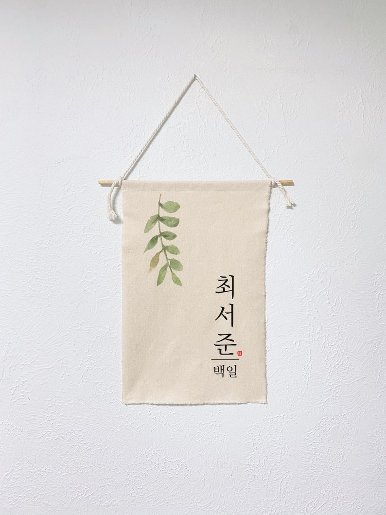 May include: A beige canvas wall hanging with a watercolor painting of green leaves and the Korean text "최선을 다할" which translates to "Do your best".