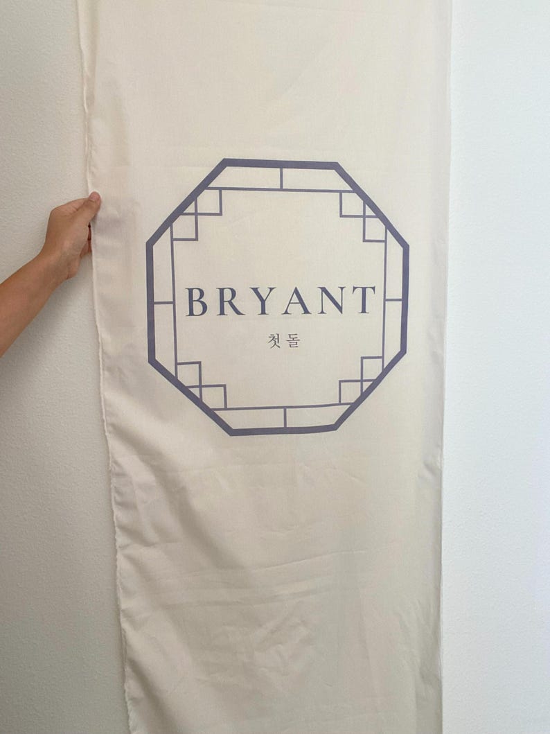 May include: A white fabric banner with a purple octagonal frame. The frame contains the text "BRYANT" and the Korean word "빛돌" in smaller font.