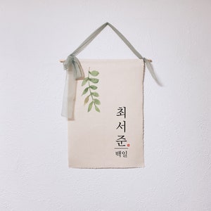 May include: A beige canvas wall hanging with a green watercolor leaf design and Korean text that reads "최선을 다할" which translates to "Do your best".