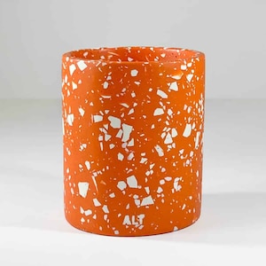 May include: Orange and white terrazzo planter with the word "ALT" in white lettering on the bottom.
