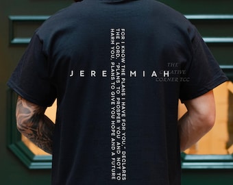 May include: Black t-shirt with white text. The word "Jeremiah" is across the back, with a vertical column of text to the right. The text reads "For I know the plans I have for you," declares the Lord, "plans to prosper you and not to harm you, plans to give you hope and a future 29:11."