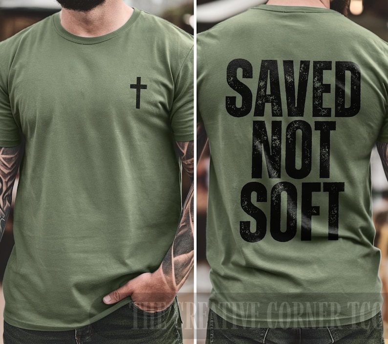 May include: Olive green t-shirt with a black cross on the front and the words "SAVED NOT SOFT" printed in black on the back. The shirt is a crew neck style.