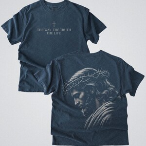 Puede incluir: Dos camisetas azul marino. La camiseta delantera tiene el texto "THE WAY THE TRUTH THE LIFE" con una cruz encima. La parte trasera de la camiseta tiene una ilustraci&oacute;n de una persona con una corona de espinas.