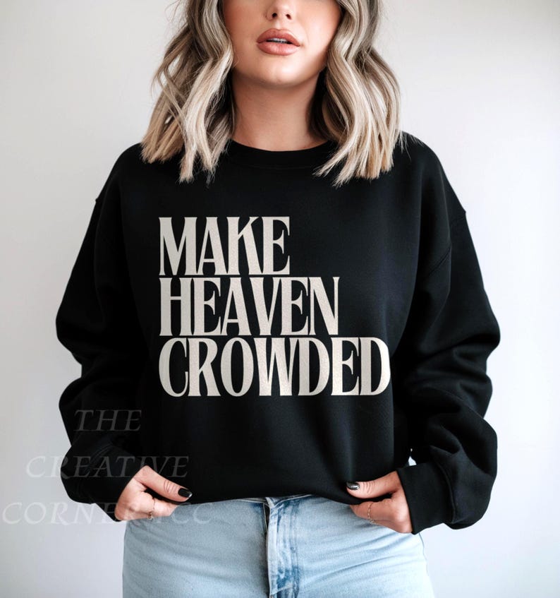 May include: Black crew neck sweatshirt featuring the text "MAKE HEAVEN CROWDED" in a bold, white font. The sweatshirt is a solid black colour and has a classic, casual style. The Creative Corner CC is printed on the bottom left.
