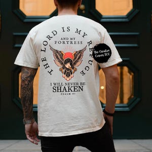 May include: A cream colored t-shirt with a graphic of an eagle with the text "The Lord is my refuge and my fortress. I will never be shaken. Psalm 91" printed on the back.
