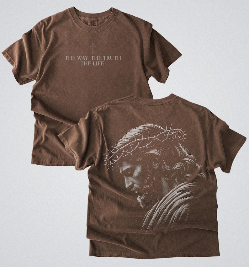 Puede incluir: Camiseta marr&oacute;n con el texto "THE WAY THE TRUTH THE LIFE" y un s&iacute;mbolo de cruz. La parte trasera de la camiseta presenta una ilustraci&oacute;n detallada en blanco y negro de una persona con una corona de espinas. La camiseta tiene un aspecto vintage y desgastado.