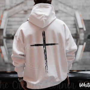 May include: White hooded sweatshirt with a black brushstroke cross design on the back.