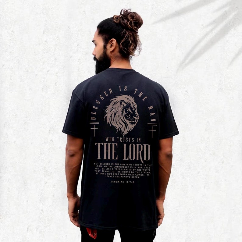 May include: Black t-shirt with a lion graphic and the text "BLESSED IS THE MAN WHO TRUSTS IN THE LORD." The shirt also features a Bible verse. The shirt is a dark color.