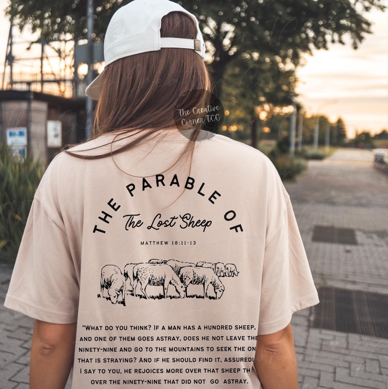 May include: A beige t-shirt with a black graphic design that says "The Parable of The Lost Sheep" with a scripture reference from Matthew 18:11-13. The graphic also includes a black and white illustration of sheep.