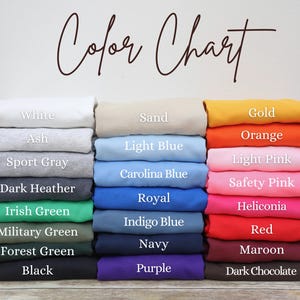 May include: Color chart showing 18 different fabric colors, including white, ash, sport gray, dark heather, Irish green, military green, forest green, black, sand, light blue, Carolina blue, royal, indigo blue, navy, purple, gold, orange, light pink, safety pink, heliconia, red, maroon, and dark chocolate.