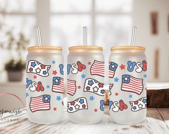 May include: Three frosted glass tumblers with bamboo lids and clear straws. Each tumbler features a red, white, and blue American flag design with stars and the word "USA" in a playful font.