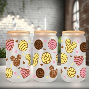 May include: Three frosted glass tumblers with bamboo lids and straws. Each tumbler features a different pattern of pink, yellow, and brown pastry designs.