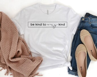 May include: White t-shirt with the text "be kind to every kind" printed in a black rectangle.