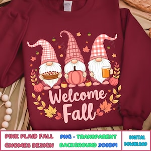 Puede incluir: Tres gnomos con sombreros de cuadros rosas se paran frente a un fondo burdeos con hojas de otoño. Los gnomos sostienen un pastel, una calabaza y una jarra de cerveza. El texto "Welcome Fall" está escrito en letras rosas debajo de los gnomos.