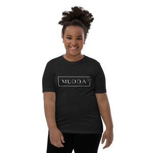 May include: A black youth t-shirt with a white rectangle that says "MUDDA" with a small white signature below it.