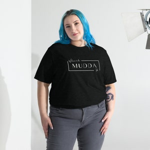 May include: A black t-shirt with white text that reads "Welcome to the MUDDA" in a white rectangle.