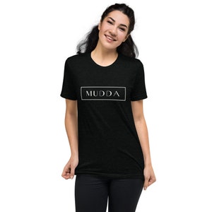 May include: A black t-shirt with a white rectangle and the word "MUDDA" printed in white inside the rectangle.