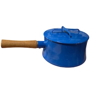 Puede incluir: Un cazo de metal esmaltado en color azul brillante con una tapa a juego que presenta un asa en forma de cruz en la parte superior. El cazo tiene un mango cilíndrico de madera largo unido al lateral, contrastando con el acabado azul brillante.