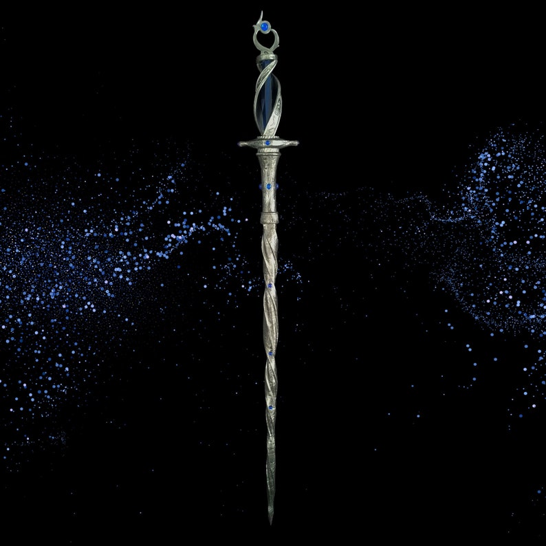 May include: A silver and blue decorative sword with a twisted blade and blue gemstone accents. The sword is set against a black background with a scattering of blue glitter.
