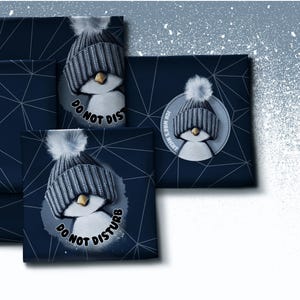 Könnte beinhalten: Dunkelblauer Stoff mit geometrischem Linienmuster und einer wiederkehrenden Illustration eines Pinguins, der eine graue Strickmütze mit Bommel trägt. Der Text DO NOT DISTURB und ICH WAR'S NICHT erscheint neben den Pinguin-Grafiken.
