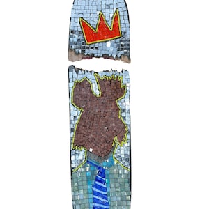 May include: A mosaic skateboard deck with a broken section. The top section features a red crown with a yellow outline. The bottom section features a mosaic portrait of a person wearing a blue and white striped tie and a light blue shirt.