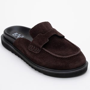 May include: Brown suede loafer-style mule with a black sole. The shoe features a rounded toe and a strap across the top. The brand name "LUVI" is visible on the insole. A stylish and comfortable footwear option.
