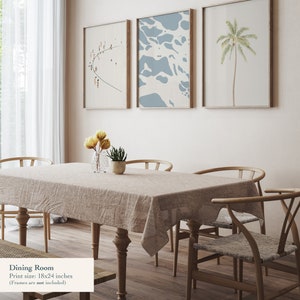 May include: A dining room with a light brown wooden table and six chairs. The table is set with a beige tablecloth and a vase of yellow flowers. Three framed prints hang on the wall behind the table. The prints feature a beach scene, a blue abstract design, and a palm tree. The text "Dining Room" and "Print size: 18x24 inches (Frames are not included)" is visible at the bottom of the image.