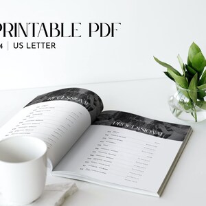 May include: An open book with the word "Processional" printed on the right page. The book is on a white surface with a white mug and a small glass vase with green leaves.