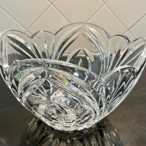 May include: A clear crystal bowl with a scalloped edge and intricate cut designs. The bowl is made of heavy, high-quality crystal and has a beautiful, elegant design.