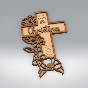 May include: Wooden cross with the name "Christina" and floral cutouts. The cross has text that reads "ZUR TAUFE" and "GOTTES SCHUTZ UND GOTTES SEGEN AUF ALL DEINEN WEGEN". The cross is made of light brown wood with darker brown accents.