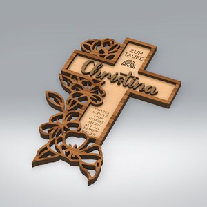 May include: Wooden cross with the name "Christina" and the words "ZUR TAUFE" and "GOTTES SCHUTZ UND GOTTES SEGEN AUF ALL DEINEN WEGEN" engraved. The cross features floral cutouts and a rainbow design. The cross is made of light brown wood.