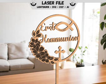 May include: A wooden cake topper with the words "Erst Kommunion" and the date 16.04.2025. The design includes a fish symbol, a cross, and a floral wreath. The topper is made of light brown wood and is designed for a religious celebration.