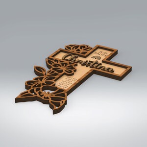 May include: Wooden cross with floral cutouts and the name "Christina" in script. The cross has a light wood center and a darker wood frame. Text on the cross reads "ZUR TAUFE" and other text in German.