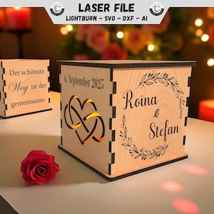 Op de afbeelding: Houten lasergesneden dozen met ingewikkelde ontwerpen, waaronder in elkaar grijpende harten en trouwringen. Eén doos toont de namen "Roina & Stefan" en de datum "6. September 2025". Een rode roos ligt in de buurt.