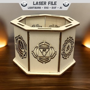May include: A white wooden hexagonal box with intricate laser cut designs of the seven chakras. The box has a lid and is ideal for storing small items.