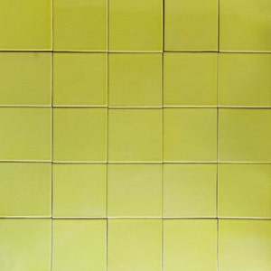 May include: A wall covered in 36 small, square, yellow tiles.