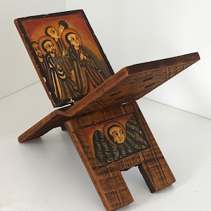 May include: A white ceramic mug with a black handle and the text "But First, Coffee" in a black, handwritten-style font. The mug is on a white surface.