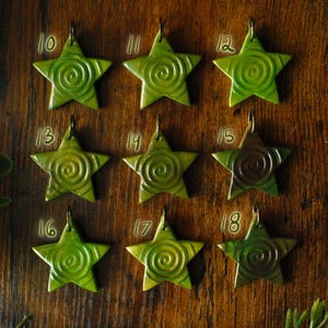Puede incluir: Un conjunto de 18 estrellas de cer&aacute;mica verde y marr&oacute;n con un dise&ntilde;o en espiral. Las estrellas est&aacute;n numeradas del 10 al 18.